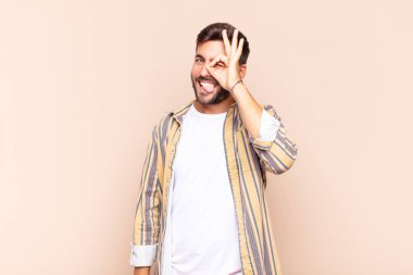 Genç adam mutlu bir şekilde gülümsüyor, şaka yapıyor ve gözetleme deliğinden bakıyor, sırları gözetliyor.