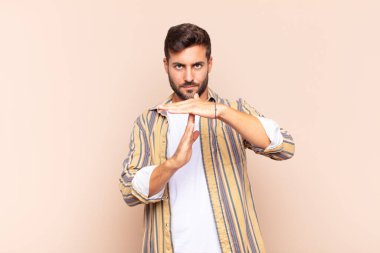 Genç adam ciddi, sert, kızgın ve hoşnutsuz görünüyor.