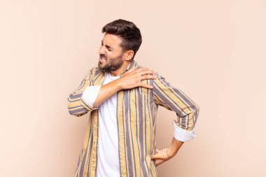 Genç adam yorgun, stresli, endişeli, hayal kırıklığına uğramış ve depresyonda, sırtı ya da boynu ağrıyan