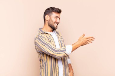 Genç adam gülümsüyor, seni selamlıyor ve başarılı bir anlaşma için el sıkışmayı teklif ediyor.