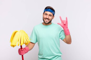 Genç adam mutlu, eğlenceli, kendinden emin, pozitif ve asi hissediyor, elle kaya veya heavy metal işareti yapıyor.