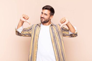 Genç adam üzgün, hayal kırıklığına uğramış ya da kızgın görünüyor. Anlaşmazlıkta baş parmaklarını gösteriyor. Hayal kırıklığına uğramış hissediyor.