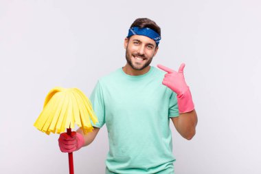 Genç adam kendinden emin bir şekilde gülümseyerek kendi geniş gülüşünü, pozitif, rahat, tatmin olmuş tavrını gösteriyor.