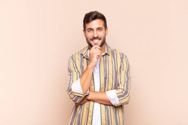 Genç adam mutlu görünüyor ve gülümsüyor. El pençe divan, merak ediyor ya da soru soruyor. Seçenekleri karşılaştırıyor.