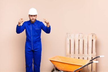 Genç adam kamerayı hem parmaklarıyla hem de kızgın bir ifadeyle sana görev yapılış konseptini yapmanı söylüyor.