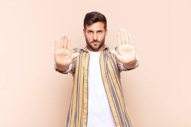 Genç adam ciddi görünüyor, mutsuz, kızgın ve hoşnutsuz giriş yasaklandı ya da her iki avuçta da dur diyor.