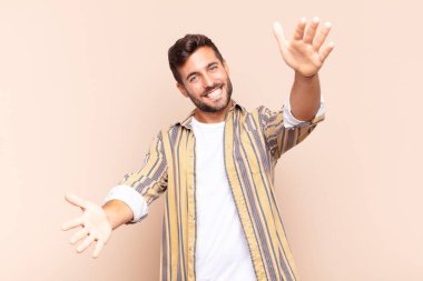 Genç adam neşeyle gülümsüyor sıcak, dostça, sevgi dolu bir kucak veriyor, mutlu ve sevimli hissediyor.