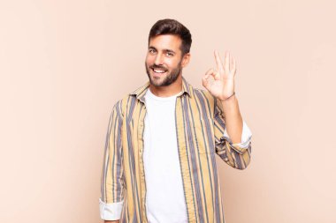 Genç adam mutlu, rahat ve tatmin olmuş hissediyor. Onayını iyi bir hareketle gösteriyor. Gülümsüyor.