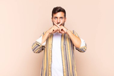 Genç adam ciddi ve hoşnutsuz görünüyor. İki parmağının önde olması reddedilerek sessizlik istiyor.