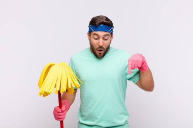 İki eliyle aşağıya bakan ağzı açık genç bir adam, şaşkın, şaşkın ve şaşırmış görünüyor.