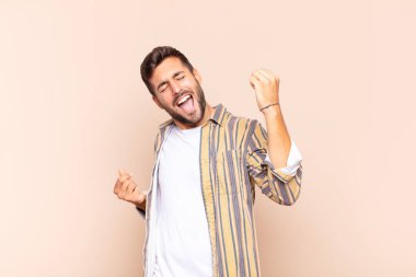 Genç adam gülümsüyor, tasasız hissediyor, rahat ve mutlu, dans ediyor ve müzik dinliyor, bir partide eğleniyor.