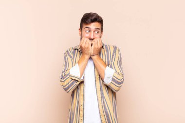 Genç adam endişeli, gergin, stresli ve korkmuş görünüyor. Tırnaklarını yiyor ve yanal fotokopi alanı arıyor.