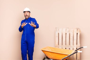 Delikanlı dehşete kapılmış, korku ve panik içinde geri çekiliyor ve kabus gibi bir inşaat konseptine tepki veriyor.