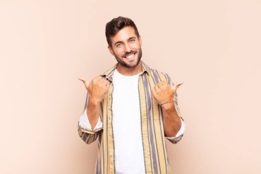 Genç adam neşeyle gülümsüyor ve mutlu görünüyor, kaygısız ve pozitif hissediyor.