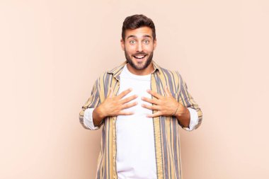 Genç adam mutlu görünüyor, şaşırmış, gururlu ve heyecanlı, kendini işaret ediyor.