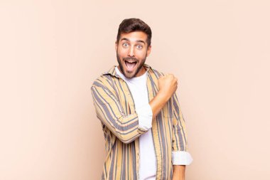 Genç adam mutlu, pozitif ve başarılı hissediyor, bir meydan okumayla karşılaştığında motive oluyor veya iyi sonuçları kutluyor.