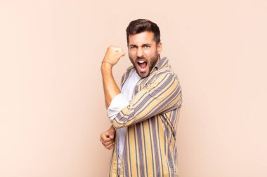 Genç adam kendini mutlu, tatmin olmuş ve güçlü hissediyor, kaslı ve formda, spor salonundan sonra güçlü görünüyor.