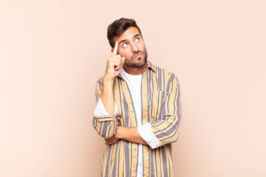 Yoğunlaşmış bakışları olan genç bir adam şüpheli bir ifadeyle yukarı ve yana bakıyor.