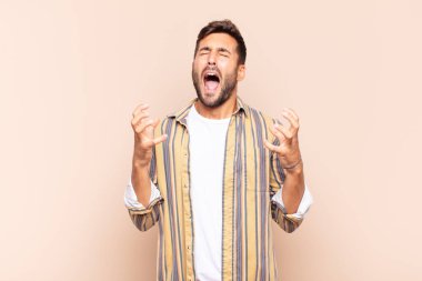 Genç adam öfkeyle bağırıyor, stresli hissediyor ve ellerini havaya kaldırıp neden ben diye bağırıyor.