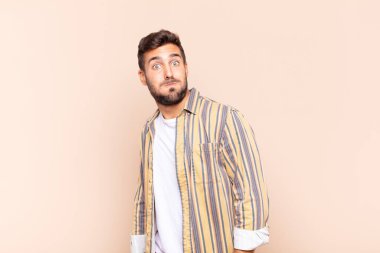 Genç adam şapşal, çılgın, şaşırmış bir ifadeyle, yanakları şişmiş, doldurulmuş, şişman ve yemekle dolu