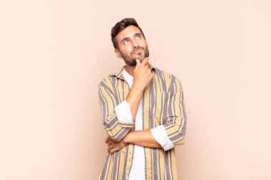 Genç adam düşünceli, meraklı ya da hayal kuruyor, hayal kuruyor ve uzayı kopyalamak için yukarı bakıyor.