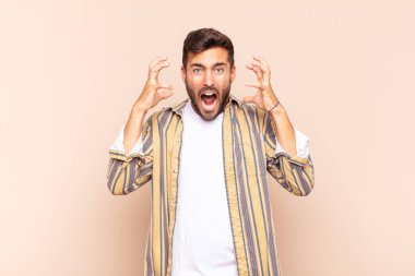 Genç adam elleri havada bağırıyor, öfkeli, sinirli, stresli ve üzgün hissediyor.