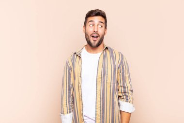 Genç adam şaşkın, mutlu, şaşkın ve şaşırmış hissediyor, ağzı açık bir şekilde yana bakıyor.