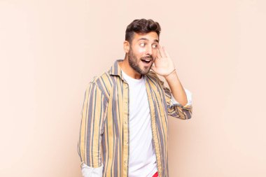 Genç adam gülümsüyor, tuhaf bir şekilde yan tarafa bakıyor, dedikoduları dinlemeye ya da bir sırrı duymaya çalışıyor.