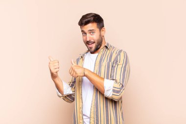 Genç adam neşeyle gülümsüyor ve yan taraftaki fotokopi alanını gösteriyor, mutlu ve tatmin olmuş hissediyor.