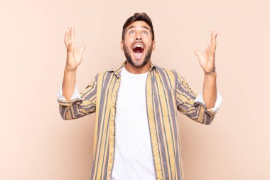 Genç adam mutlu, şaşkın, şanslı ve şaşırmış hissediyor, zaferi kutluyor, iki eli havada.