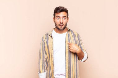 Genç adam şaşkın, şaşkın ve güvensiz hissediyor, kendini göstererek kim olduğunu soruyor, ben mi??