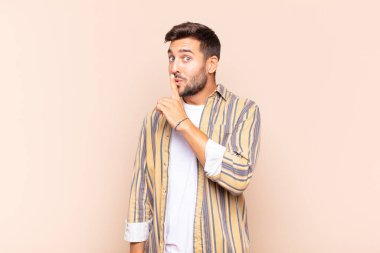 Genç adam sessizlik ve sessizlik istiyor, parmaklarıyla ağzının önünde işaret ediyor, 