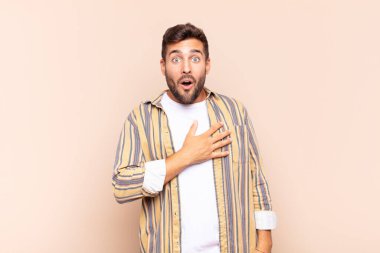 Genç adam şok olmuş ve şaşırmış hissediyor, gülümsüyor, el ele tutuşuyor, o olmaktan ya da minnettarlık göstermekten mutlu.