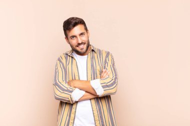 Genç adam neşeli bir şekilde gülümsüyor. Olumlu, mutlu, kendinden emin ve rahat bir ifadeyle.