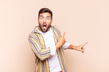 Delikanlı şaşkın ve şaşırmış hissediyor. Kenardaki fotokopi alanını işaret ediyor. Şaşırmış ve ağzı açık bakıyor.