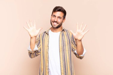 Genç adam gülümsüyor ve arkadaş canlısı görünüyor, onuncu ya da onuncu numarayı gösteriyor, eli önde, geri sayıyor.