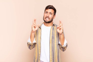 Genç adam endişeyle dua ediyor ve endişeli bir bakışla iyi şanslar diliyor.