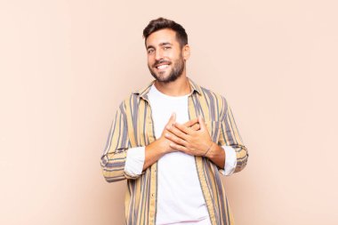 Genç adam romantik, mutlu ve aşık, neşeyle gülümseyen ve kalbe yakın el ele tutuşan