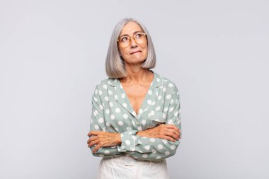 Gri saçlı kadın kuşkulanıyor ya da düşünüyor, dudağını ısırıyor ve kendini güvensiz ve gergin hissediyor.