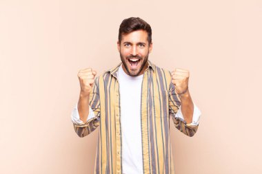 Genç adam mutlu, şaşırmış ve gururlu, bağırıyor ve başarıyı büyük bir gülümsemeyle kutluyor.