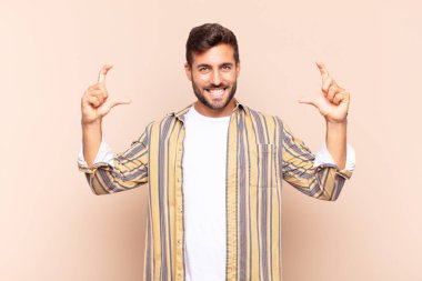 Genç adam kendi gülüşünü iki eliyle çiziyor, olumlu ve mutlu görünüyor, sağIık kavramı