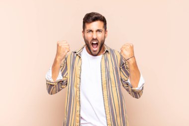 Genç adam öfkeli bir ifadeyle ya da yumruklarıyla başarıyı kutlarken agresif bir şekilde bağırıyor.