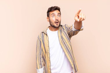 Genç adam şaşkın ve şaşırmış hissediyor, şaşırmış ve hayranlıkla yukarı bakıyor, şaşkın, açık ağızlı bir bakışla