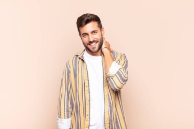 Genç adam neşeli ve kendinden emin bir şekilde gülüyor. Sıradan, mutlu, dostane bir gülümsemeyle.