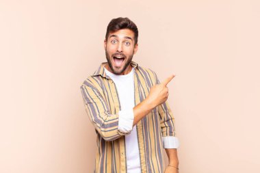 Genç adam heyecanlı ve şaşırmış görünüyor. Yana ve yukarıya doğru uzayı gösteriyor.