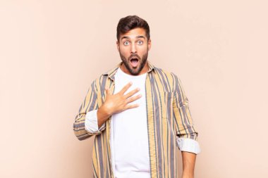 Genç adam şaşkın, şaşkın ve şaşırmış hissediyor, elleri göğsünde ve ağzı açık, diyor ki, kim, ben?