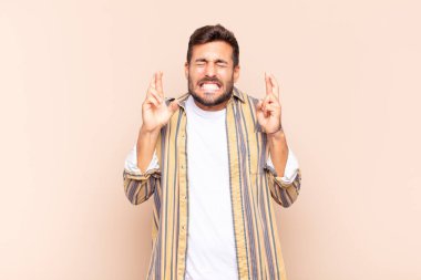 Genç adam gülümsüyor ve endişeyle iki parmağını çapraz yapıyor. Endişeli ve iyi şanslar diliyor.