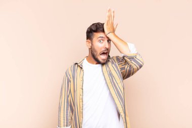 young man raising palm to forehead thinking oops, after making a stupid mistake or remembering, feeling dumb