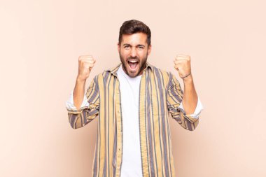 Genç adam mutlu, pozitif ve başarılı hissediyor, zaferi, başarıları ya da iyi şansı kutluyor.