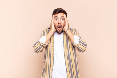 Genç adam mutsuz, korkmuş ya da endişeli görünüyor, ağzı sonuna kadar açık ve iki kulağını da elleriyle kapatıyor.